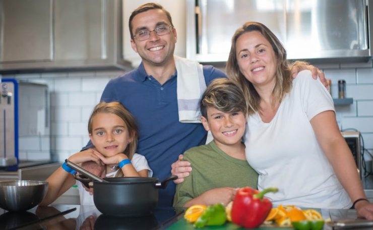 A joyful family of four cooking together in a modern kitchen, highlighting family bonding and culinary activities.